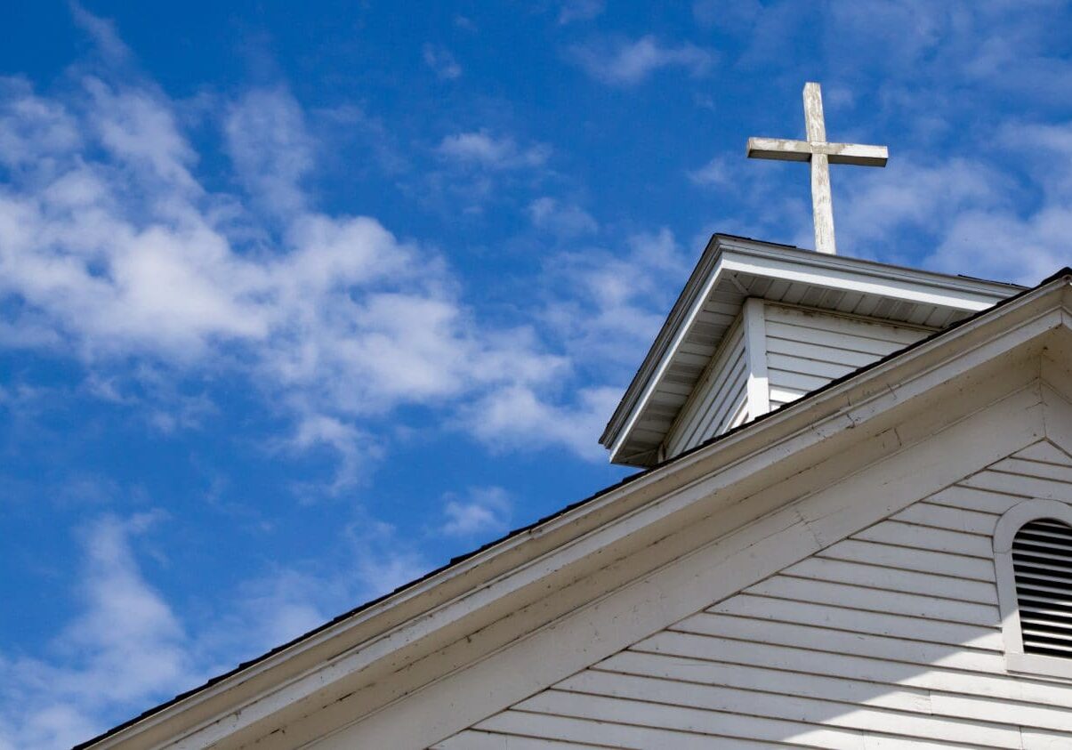 Church steeple with cross against blue sky.