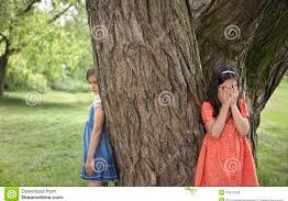 Children playing hide and seek by tree.