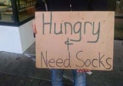 Person holding cardboard sign reading "Hungry Need Socks