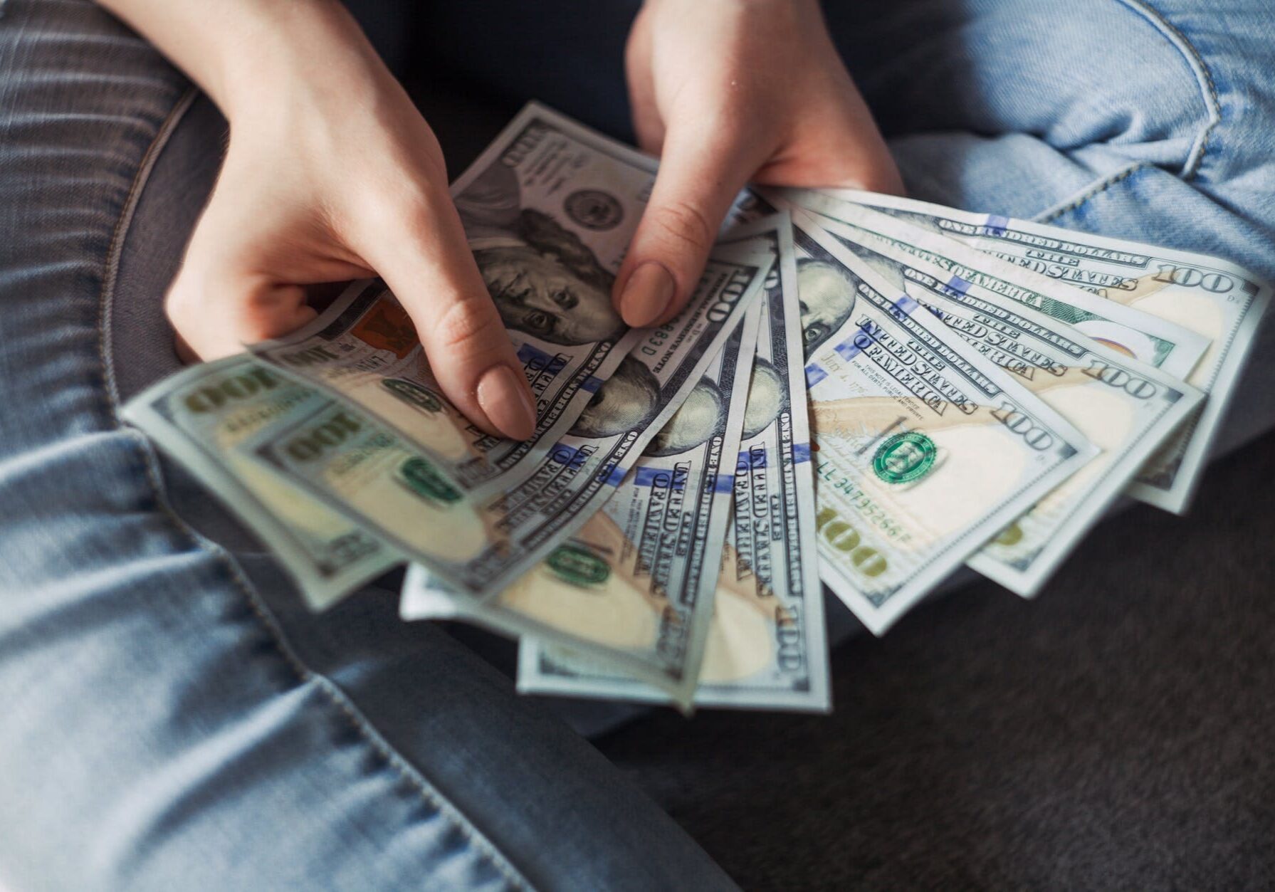 Hands fanning US hundred-dollar bills