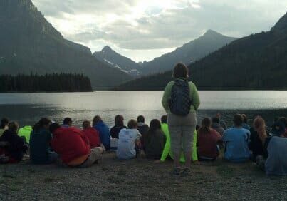 Group of people sitting by a lake.