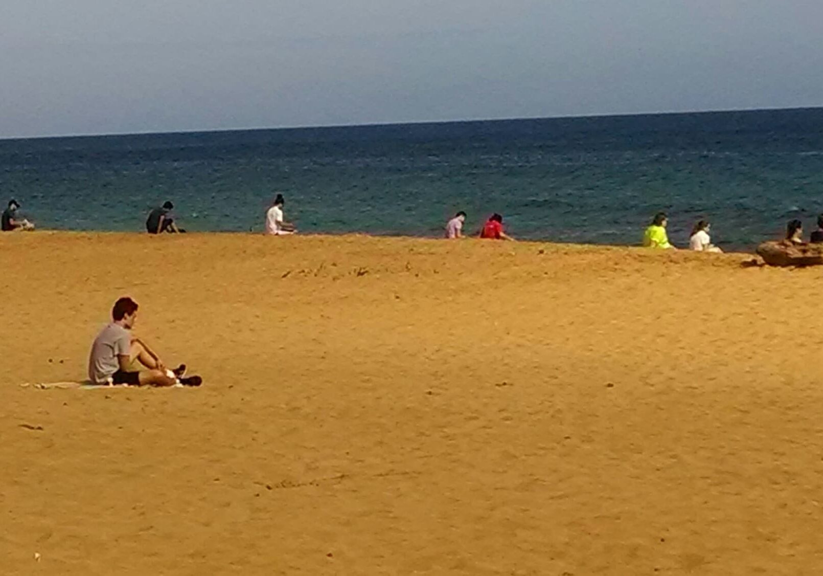 People sitting on sandy beach by ocean